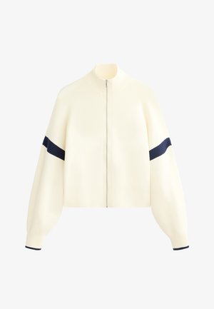 Kremljasta zip-up jopica z visokim ovratnikom, širokimi rokavi in mornarskimi črtami na rokavih. Mehka tekstura in skrajšana zasnova.