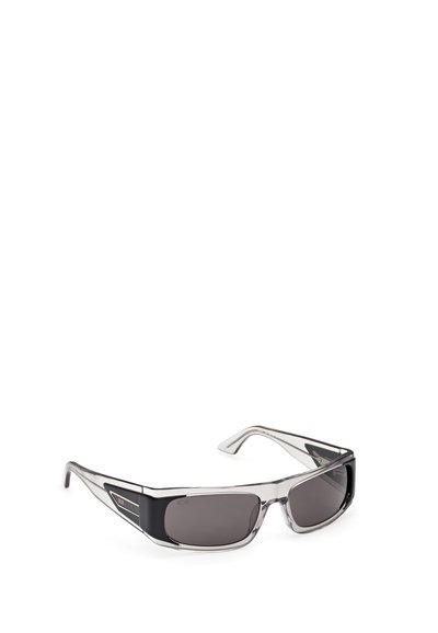 Gafas de sol rectangulares con montura transparente gris ahumada y lentes oscuras, con acentos negros y logo en las patillas.