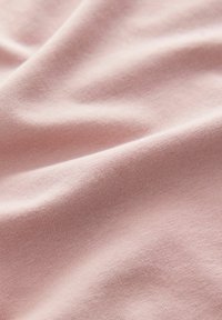 Tela de un suave color rosa con una textura lisa y elástica, y un sutil patrón de relieve, que muestra pliegues suaves y una apariencia ligera.