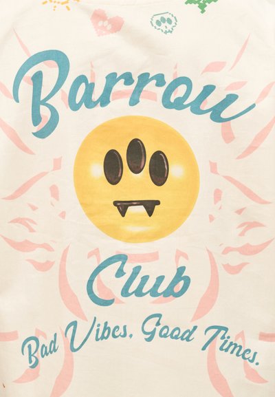 Κίτρινο χαμογελαστό πρόσωπο με τρία μαύρα μάτια και βαμπιρικά δόντια, περιβαλλόμενο από μπλε κείμενο "Barroi Club" και "Bad Vibes, Good Times" σε λευκό φόντο.