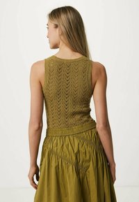 Olivgrön, ärmlös stickad topp med ett chevronmönster, som matchas med en insamlad kjol med textilstruktur och elastisk midjeband.