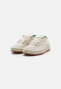 Beez suedesneakerid roheliste aktsentidega, ümar varvas, valged paelad ja gummi kummipõhi, millel on kontrastse õmblusega.