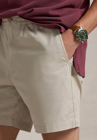 Ljusbeige bomullsshorts med resår i midjan, sidfickor och liten logodetalj på fållen. Matchas med en vinröd topp och klocka.