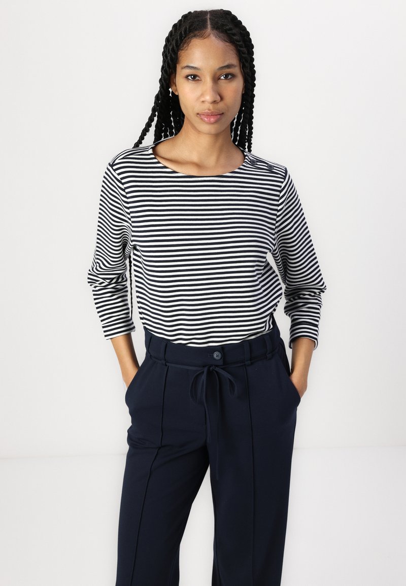 Koszula z długim rękawem w czarno-białe poziome paski, połączona z spodniami w colorze granatowym z wysokim stanem i wiązanym paskiem.