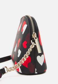 Borsa a tracolla triangolare nera con motivi a cuori rossi e bianchi, dotata di una cerniera oro e una tracolla a catena. Materiale in pelle sintetica testurizzata.