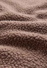 Soft, brown, curly fleece fabric with a textured, dense pile and gentle folds creating a plush, cozy surface.