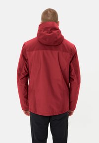 Veste imperméable rouge avec capuche, présentant une texture lisse, des poignets ajustables et deux poches latérales. Vue de dos affichée.