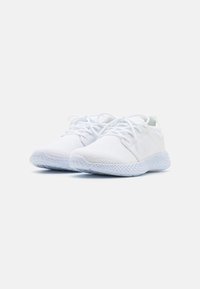 Baskets de sport blanches avec une tige en mesh texturé et un bout rond. Elles disposent de lacets plats et d'une semelle en caoutchouc de couleur claire avec un motif tissé.