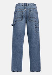 Jean charpentier en denim bleu avec poches plaquées arrière, boucle latérale pour outils et poche cargo sur la jambe droite.