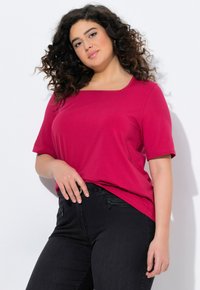 Haut magenta à manches courtes avec un décolleté carré, associé à un jeans noir. Présente une coupe décontractée et un matériau en coton doux et lisse.