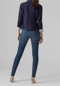 Námornická sako s proužkovanými manžetami, spárované s úzkými modrými džíny. Slim-fit design s zadními kapsami, jemným vyblednutím a délka až k kotníkům.