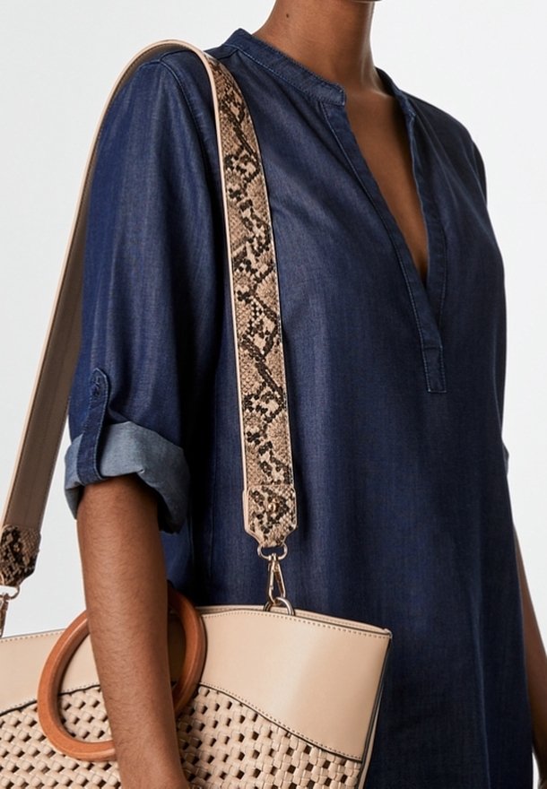 Jeansowa bluzka z plisą i podwiniętymi rękawami, w parze z beżową torebką o tkanej fakturze i paskiem w wężowy wzór.