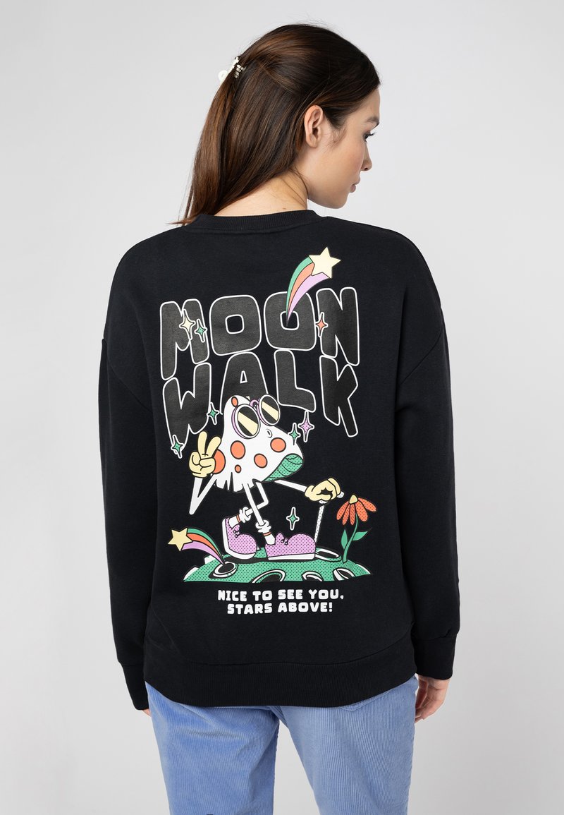 Schwarzer Sweatshirt mit einem bunten Grafikdruck auf der Rückseite, der eine Cartoonfigur mit einem Peace-Zeichen, Blumen und Text darstellt.