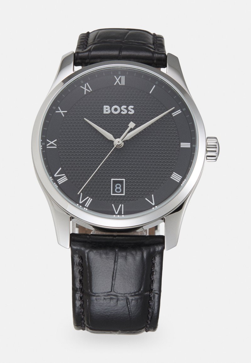 Reloj con correa de cuero negro, esfera negra texturizada, manecillas en tono plateado, números romanos y display de fecha a las 6 en punto; caja de acero inoxidable.
