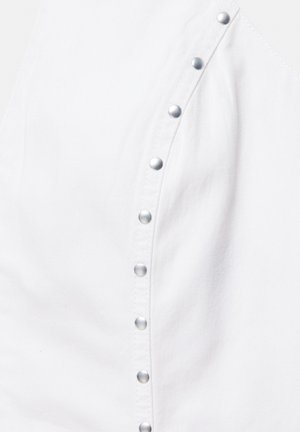 White fabric with a diagonal row of silver metal snap buttons fastening a garment, highlighting texture and seam detail.
