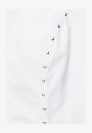 White fabric with a diagonal row of silver metal snap buttons fastening a garment, highlighting texture and seam detail.