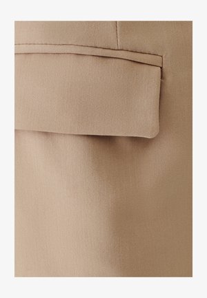 Beež kangas sileda tekstuuriga, millel on klapiga tasku, millel on puhas ja korrastatud äär. Üldine disain on lihtne ja funktsionaalne.