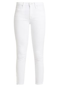 Jeans skinny blancos hechos de denim elástico, con una cinturilla de talle alto, cremalleras laterales en los tobillos y una superficie suave y texturizada.