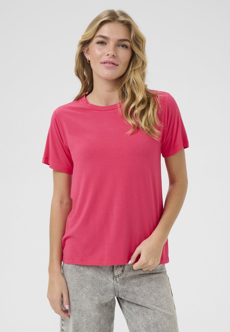 T-shirt rose à manches courtes en tissu lisse, avec un col rond et une coupe décontractée. Assorti à un jean gris clair.