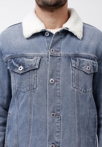 Leren spijkerjack in lichtblauw met een crèmekleurige fleece kraag. Beschikt over twee borstzakken en vijf knopen met contrasterende stikdetails.