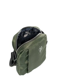 Kompaktowa oliwkowozielona torebka na ramię z otwartym głównym suwakiem, przednią kieszenią na zamek, czarnym regulowanym paskiem oraz nadrukowanym wnętrzem podszewki.
