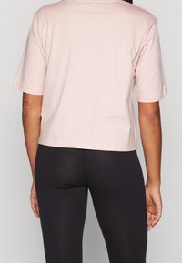Ljus rosa, kortärmad t-shirt gjord av mjuk bomull, med en avslappnad passform och rak fåll. Bärs med svarta leggings.