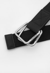 Curea elastică neagră cu o cataramă din metal argintiu cu brand. Textură netedă și finisaj durabil, cu un element de prindere rectangular.