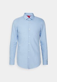 Chemise bleu clair à manches longues avec col classique, présentée sur fond blanc uni.