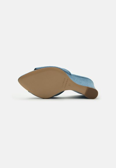 Pantof de piele suede albastru, cu vârful într-o formă de migdală și talpa de cauciuc bej. Tocul este jos și ușor curbat pentru confort.