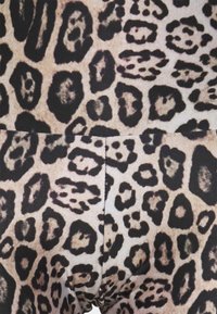 Läderklädsels tyg i leopardsyfte med stora svarta fläckar på en beige bakgrund. Mjuk textur med en sömlös design som visar varierad mönsterdetalj.