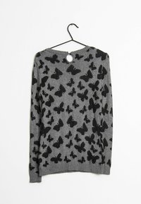 Pull gris avec motif de papillon noir, encolure ronde et fermeture à bouton au dos. Fabriqué dans un matériau en maille texturée.