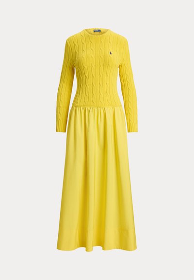 Κίτρινο πλεκτό φόρεμα με ζακάρ πάνω μέρος και μακριά μανίκια, που συνεχίζει σε ένα μοιρασμένο, φουσκωτό φούστα. Διαθέτει ένα μικρό λογότυπο στο στήθος.