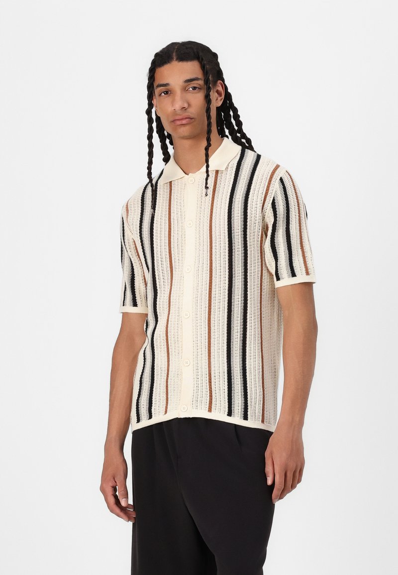Kurzarm-Polohemd in Creme mit horizontalen Streifen in Schwarz, Braun und Orange, aus strukturiertem Strick und mit Knopfverschluss.