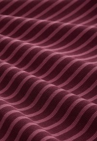 Tissu présentant un motif ondulé dans des teintes de bordeaux profond et de rose clair, avec une texture côtelée créant des lignes en relief.