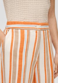 Gestreepte broek met oranje, beige en blauwe strepen. Heeft een brede tailleband, zijzakken en een knoopsluiting. Textuurstof.