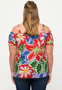 Barevná květinová blůza s off-shoulder designem, krátkými nařasenými rukávy a levandulovým pozadím. Vzor zahrnuje velké červené květiny.