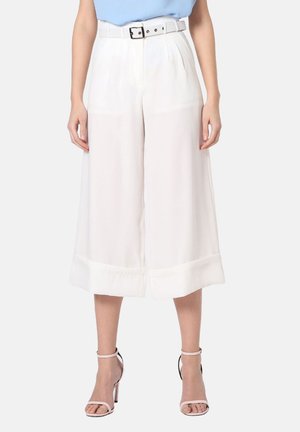 Pantalones anchos blancos con una textura suave, pliegues en la parte delantera y un cinturón a juego. Presenta puños vueltos y un corte holgado.