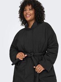 Svart, vadderad ytterjacka med hög krage, långa ärmar och midjeband. Har en slät yta och framfickor.