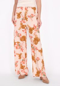 Blumenfarbene weit geschnittene Hosen aus leichtem Stoff, mit einem rosa Hintergrund und braunen sowie korallenfarbenen Blumen, sowie einem elastischen Bund.