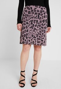Leopardmönstrad kjol i dämpad lila tyg, knälång med en lätt A-linjeform. Svarta remsandaler kompletterar outfiten.