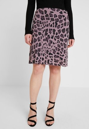 Falda de leopardo en tela morada apagada, hasta la rodilla y con una ligera forma en A. Tacones negros de tiras complementan el atuendo.