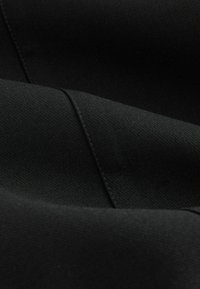 Tessuto nero con una superficie liscia, caratterizzato da morbide pieghe e cuciture. Il materiale appare elastico e resistente, adatto per l'abbigliamento.
