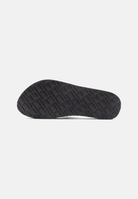Semelle de chaussure en caoutchouc noir présentant une surface texturée et un motif en forme de grille avec un orteil arrondi, offrant traction et durabilité.