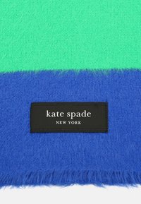 Rätik pehme ja koheva tekstuuriga, roheliste ja siniste horisontaalsete triipudega, musta sildiga, kus on kirjas "kate spade NEW YORK".