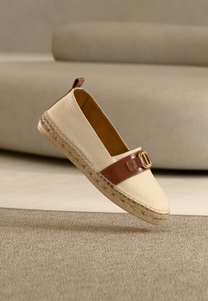 Espadrille en toile beige avec bride en cuir marron et boucle dorée, dotée d'une semelle en jute tressé et d'une doublure intérieure lisse.
