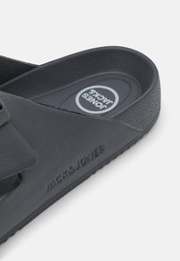 Mustad must sandaal laia rihmaga, tekstureeritud pealispinna ja logo detailiga taldadel. Omab mugavust pakkuvat kontuuritud tallapinda.