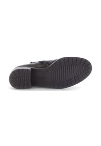 Zapato de cuero negro con suela de goma texturizada, con bandas elásticas horizontales para un mejor ajuste y puntera redonda.