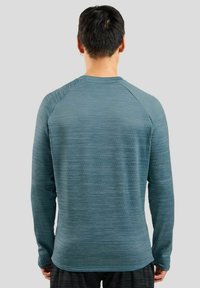 Langarm, blauwe sportshirt van een textuurstof, met ribbelaccenten op de schouders en een gebogen rand. Ontspannen pasvorm, lichte stof.