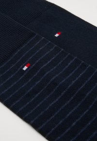 Marineblaue Socken mit einem strukturierten oberen Abschnitt und einem gestreiften unteren Abschnitt, mit einem kleinen rot, weiß und blauen Logo.