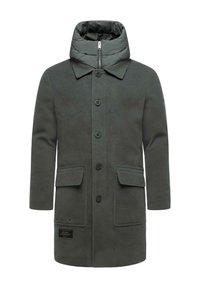 Cappotto verde imbottito con colletto alto, chiusura con bottoni, due tasche frontali e un tessuto testurizzato. Presenta un'etichetta sul lato sinistro in basso.